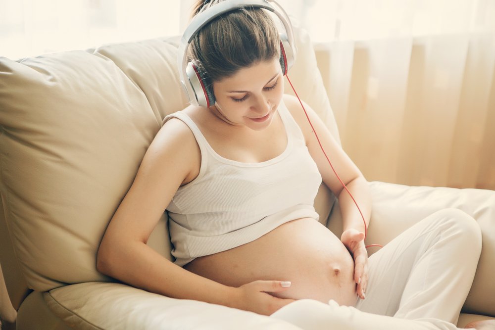 Madre embarazada acariciando barriguita mientras escucha música