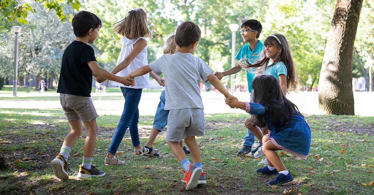 Niños y niñas jugando alegres haciendo corro cogidos de la mano