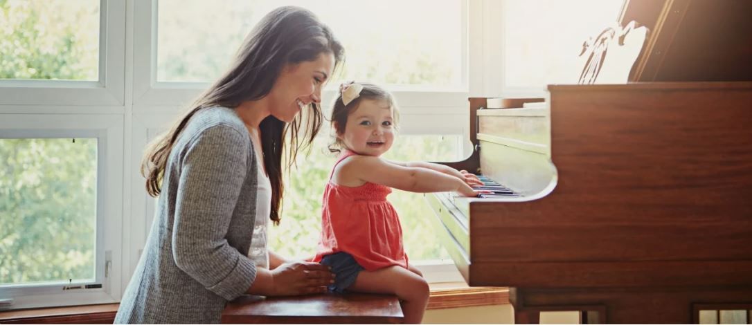 Niña toca piano junto a mamá