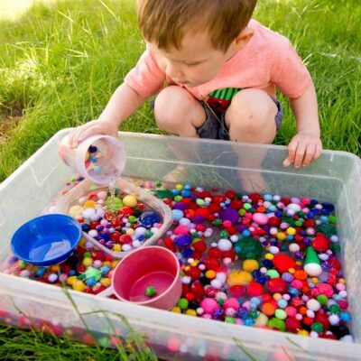 Niño jugando con recipiente agua bolas de colores cubos