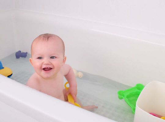 Bebe sonriendo disfrutando de un divertido baño con sus juguetes