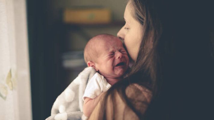 Mamá toma en brazos a bebé que llora